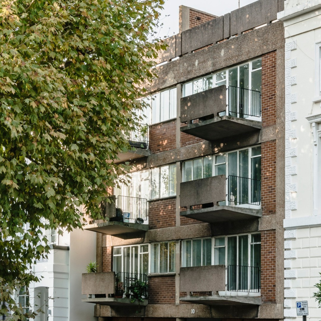 An apartment block shaded by a large oak tree